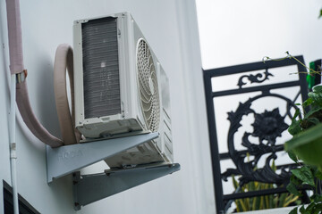 Outdoor unit of a split air conditioning system mounted on a white exterior wall