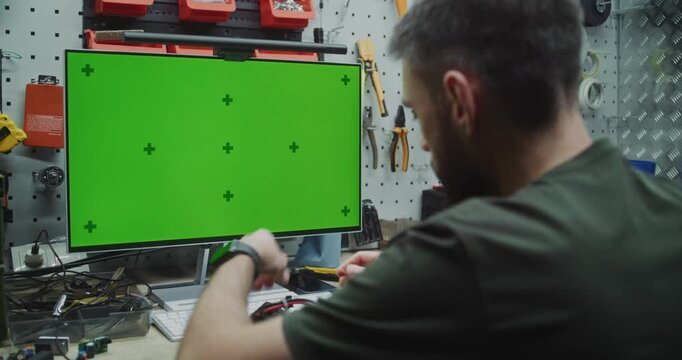 Engineer Working on Drone With Chromakey Placeholder Display. Green Screen Monitor With Tracking Markers Visible of Engineer Assembling Drone. Custom Software, Data, or Virtual Reality Interfaces.