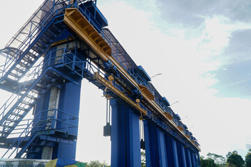 Large Blue and Yellow Industrial Dam Structure with Staircases Against Bright Sky