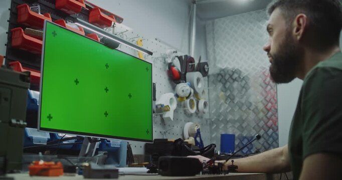 Engineer Using Green Screen For 3D Modeling And Design Software. Engineer Engrossed In Physical Assembly Of Drone While Utilizing Monitor With Green Screen For 3D Modeling, Flight Simulation Software.