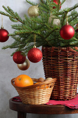 Christmas still life with fir branches in a basket, decorated with Christmas balls and a basket with oranges