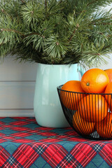 New Year's table with pine branches and oranges on a red checkered tablecloth