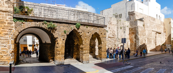 Cadiz, Spain - April 16, 2025: medieval walls in Cadiz, with tourists swimming in the sea during the Easter holidays in Cadiz, Spain. © josevgluis