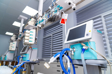 Several medical devices are lined up in a hospital room. They are ready for use by healthcare staff. Bright lights illuminate the space, making it functional for patient treatment