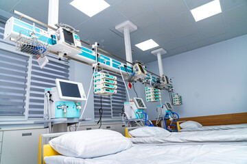 Two empty beds are placed in a hospital room. Medical machines are mounted on the wall, ready for patient use. The space is bright and clean, designed for medical care