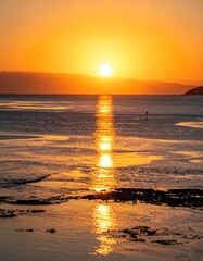 Naklejka premium Golden sunset reflecting on tranquil water, encompassing a distant shore