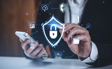 Businessman interacting with digital hologram of cybersecurity shield on futuristic background for data protection concept.