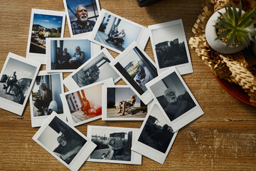 Collection of printed photos laid out on a wooden table showing moments of everyday life and people engaged in various activities