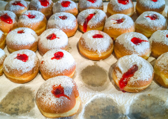 Morning sale of sweet donuts (sufganiot) for Hanukkah Jewish Holiday, close-up shot done in a local market place in bakery. Focus on foreground 