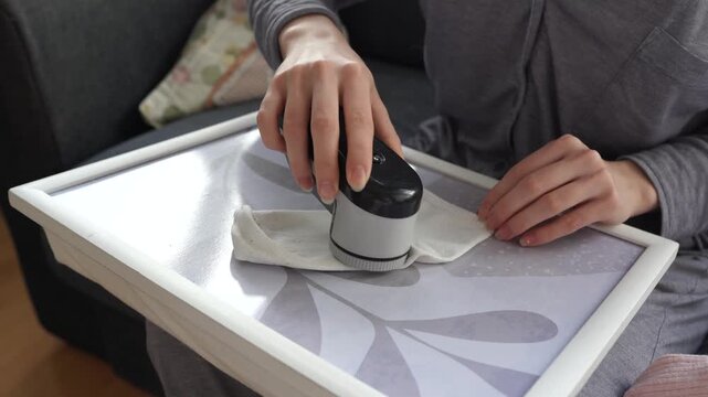 woman takes care of clothes at home, cuts off lint with tool