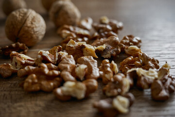Walnuts on wooden table scattered with whole walnuts nearby during afternoon light