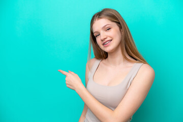 Fototapeta premium Teenager Russian girl isolated on blue background pointing back