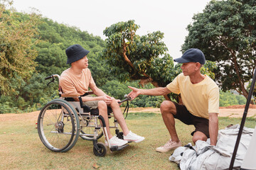 A caregiver assists a wheelchair user during camping setup at a scenic outdoor location. They share teamwork, trust, and inclusion while enjoying accessible travel and a relaxed lifestyle in nature.