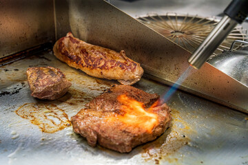 The chef at the restaurant kitchen flame the steak with fire at the final preparation