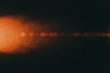 Orange colored lens flare effect on black background