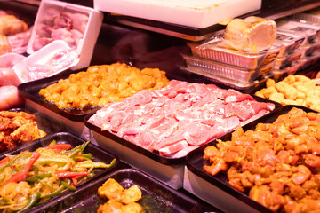 Different types of marinated meat and vegetables on display at grocery supermarket