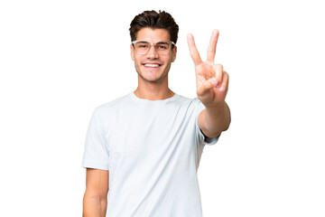 Naklejka premium Young caucasian handsome man over isolated background smiling and showing victory sign