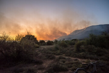 red clouds of smoke of wildfire at dusk on mountain slopes, near Camdeboo, South Africa