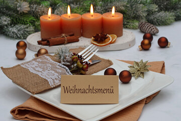Festlich gedeckter Tisch mit Kerzen, Weihnachtskugeln,Tischgedeck und einer Karte mit der Beschriftung Weihnachtsmenü.