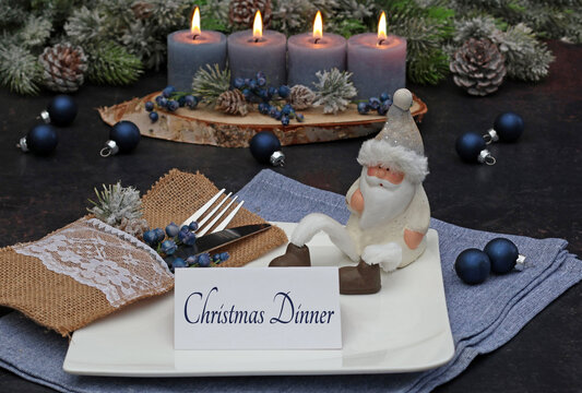 A festively set table with candles, Christmas baubles, tablecloth and a card labeled "Christmas Dinner".