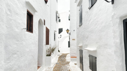 Fototapeta premium Narrow cobblestone street with whitewashed houses in the traditional fishing village of Binibeca Vell, Menorca.