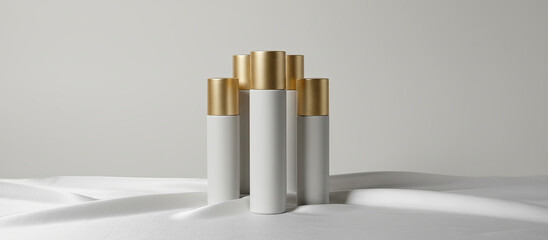 Luxury cosmetic product mockup with white tubes and gold caps on elegant white draped fabric