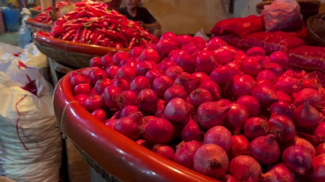 Close-up detail of fresh red shallots in a container at a traditional market.