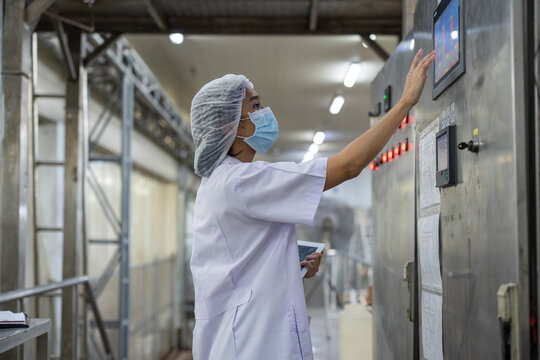 Female inspector wearing protective gear and hairnet examines canned fish production quality, checks Industrial pressure cooker, monitors food processing , and records data using tablet. - Powered by Adobe
