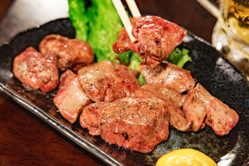 箸で持ち上げられた照り焼き風の濃厚な鶏レバー（レバー焼き