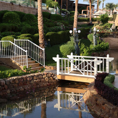 green area with a garden and bridge over a pond.