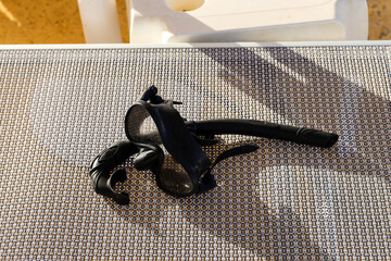 A diving mask left on a hotel sunbed.
