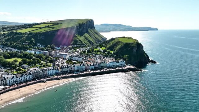 Coastal town nestled between sea and cliffs under a bright blue sky, aerial view shows beach and buildings
