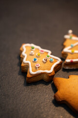 Freshly baked Christmas cookies laying spread on clean black kitchen table with neat and carefully placed decorations