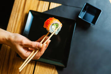 Hand Lifting Fresh Sushi Roll Over Black Plate © Aliaksandr