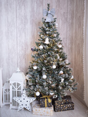 Festively decorated Christmas tree adorned with white ornaments and a silver bow, surrounded by beautifully wrapped gifts and lanterns, creating a cozy holiday atmosphere
