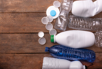 Various plastic bottles and caps arranged on a wooden surface, showcasing recycling potential and environmental awareness, emphasizing sustainability and waste reduction efforts