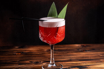Red cocktail with foam garnish in crystal glass