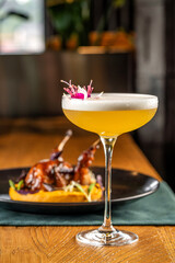 Golden cocktail with foam and floral garnish