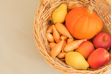 Warm tones. Orange pumpkin, apples, pears and shallots in a wicker basket. Fall colors and still life. Top view.