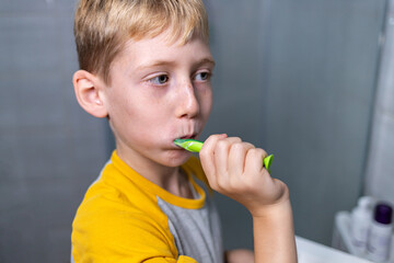 Young boy brushing his teeth in the bathroom at home, close-up scene illustrating daily hygiene and morning routine.