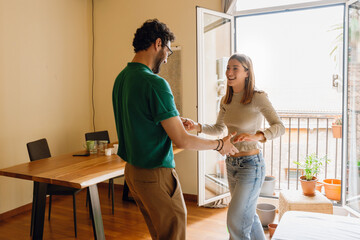 Obraz premium A woman laughs and holds hands with a man across from her as they dance