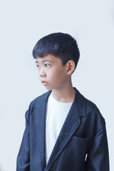 A photograph of a small Asian boy in a suit against a white background.