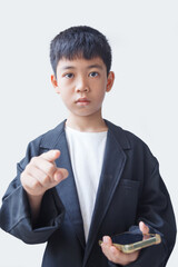 Little asian boy holding mobile phone and pointing at camera isolated on white background