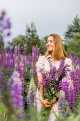 Young woman walking in blooming lupine field on summer day