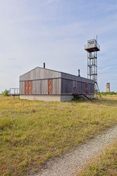 Former Soviet border guard post or watchtower and building with Loode lighthouse in the background in summer with blue sky with light clouds, T&uuml;rju, Saaremaa, Estonia.
