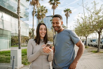 Male and female athletes laughing and talking while looking at the phone she is showing