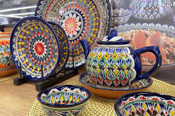 A teapot with an oriental pattern on the shelf of a kitchenware store.