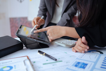 Business team reviewing financial data on digital tablet with stylus, discussing charts and reports at office desk, modern teamwork, analytics, budgeting, and strategic planning concept.