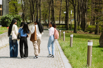 A group of three female students listen to a female student talking while walking next to them