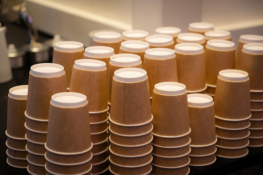 Brown paper coffee cups neatly arranged and stacked on a counter, ready for use in a cafe or event, emphasizing catering, organization, and sustainability